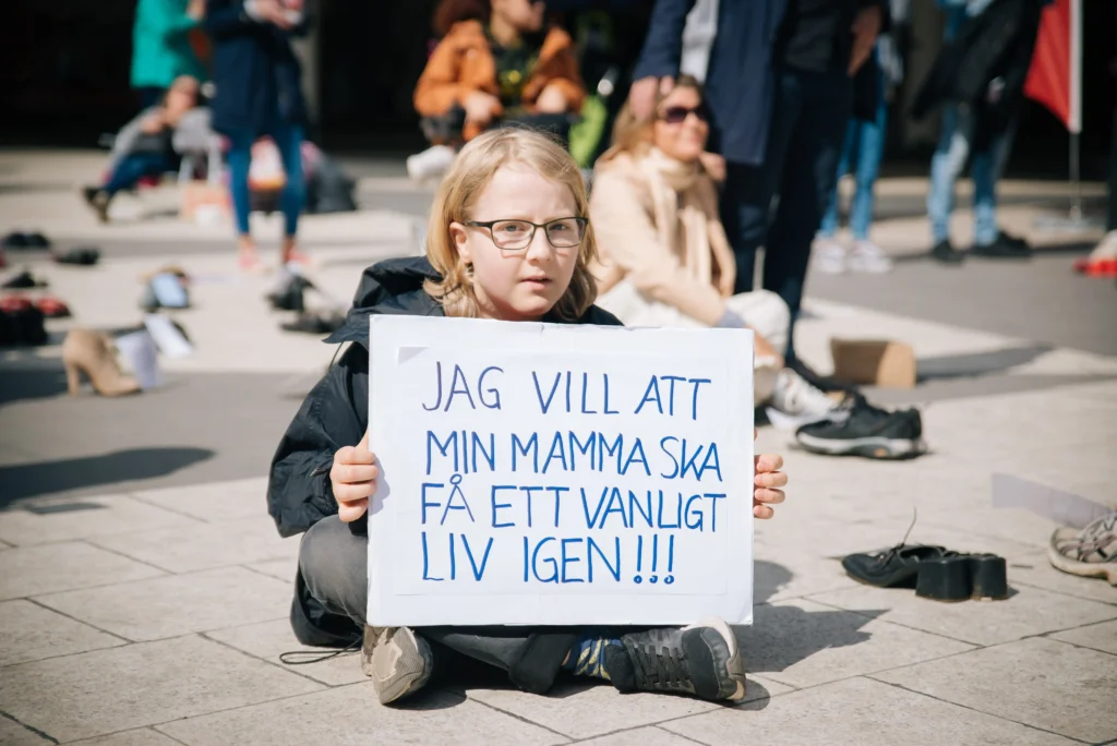 Barn med skylt "Jag vill att mamma ska få ett vanligt liv igen"